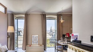 A modern living room with a sofa, a dining table with chairs, a framed artwork, and a view of the city through large windows. - City and the Sea in Genova (Genoa)