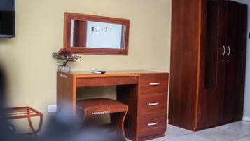 A wooden desk with a mirror, drawers, and a small plant.