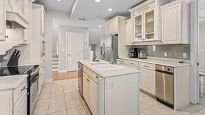 A modern kitchen with white cabinetry, stainless steel appliances, and a central island.