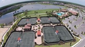 Vista aérea de un campo de golf con varias canchas de tenis, una piscina y edificios circundantes.
