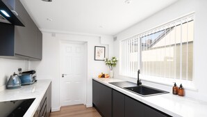 A modern kitchen with a white countertop, black cabinets, and a black sink. - Perfect Modern 4 bedroom House in Liverpool with Garden - Free Wi-Fi - Parking (Tuebrook)