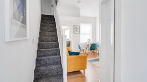 A staircase leading to a dining area with a yellow sofa and teal chairs. - Perfect Modern 4 bedroom House in Liverpool with Garden - Free Wi-Fi - Parking (Tuebrook)