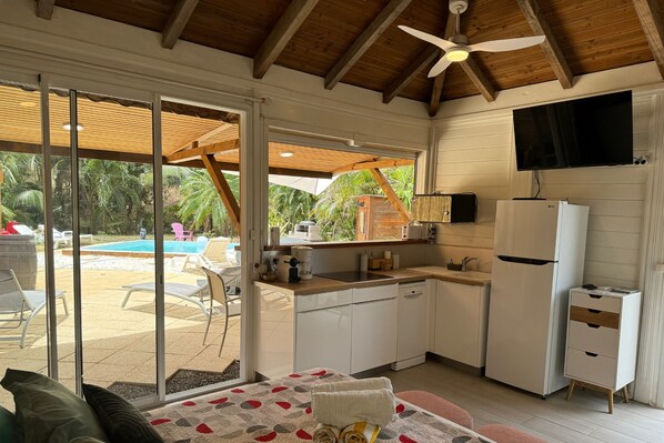Enjoy a compact room with a kitchenette, sofa, and dining table, plus a patio with pool and outdoor seating.