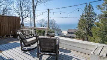 Relax on the deck with a wicker chair and small table overlooking a serene body of water.