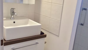 A bathroom with a white sink, a mirror, and a shower. - Maison Entre LAC ET Ocean A Hourtin EN Gironde, Idéal Avec de Jeunes Enfants ! (Hourtin)