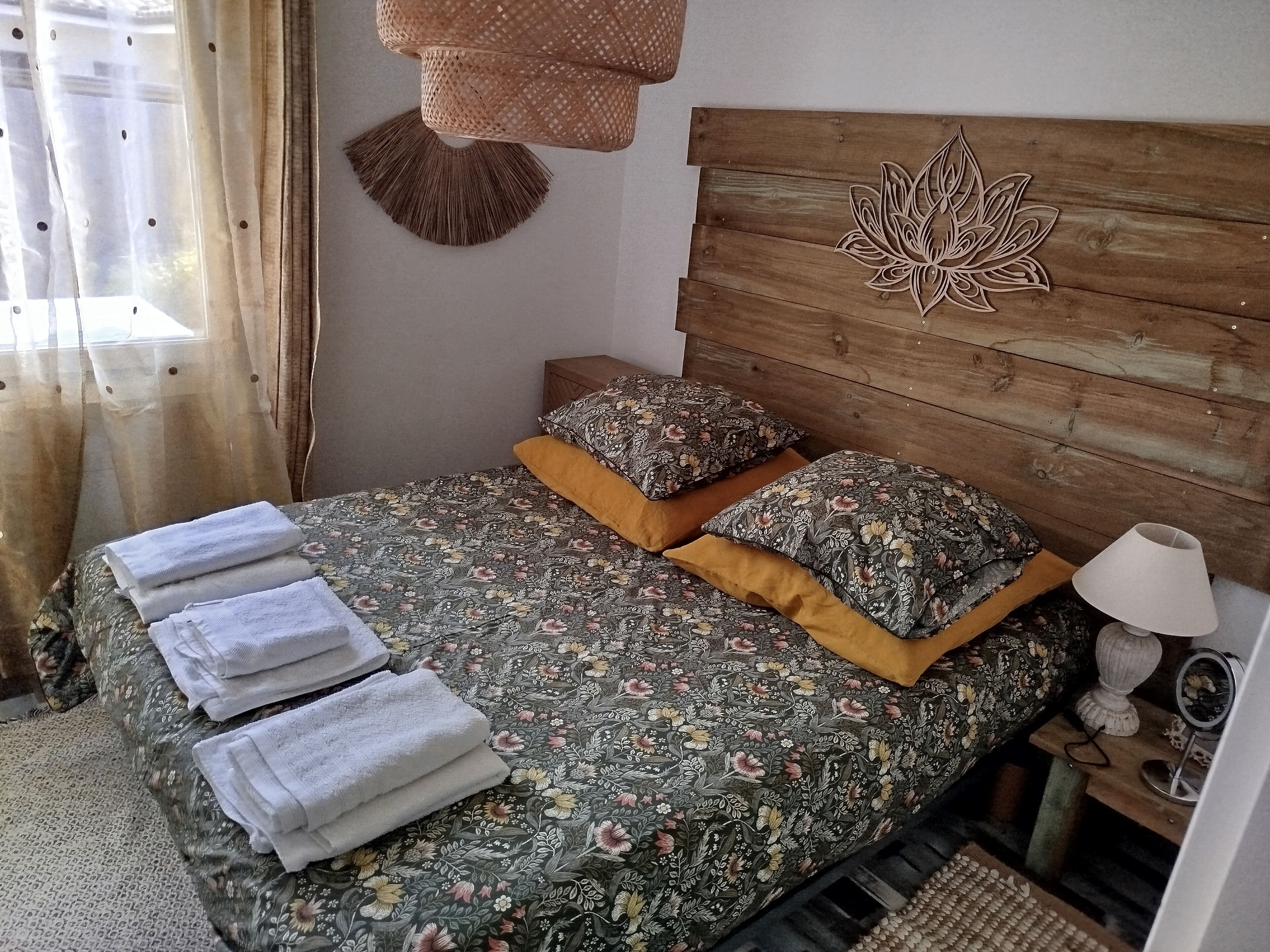 Un letto rifatto con lenzuola a fiori, due cuscini e asciugamani piegati.