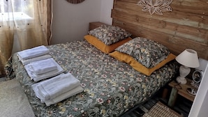 A neatly made bed with floral bedding, two pillows, and folded towels. - Maison Entre LAC ET Ocean A Hourtin EN Gironde, Idéal Avec de Jeunes Enfants ! (Hourtin)