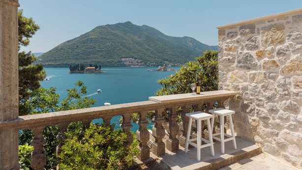 A balcony with a stone balustrade overlooking a lake with boats and a mountain in the background. - Step to Kotor Bay Perast (Perast)