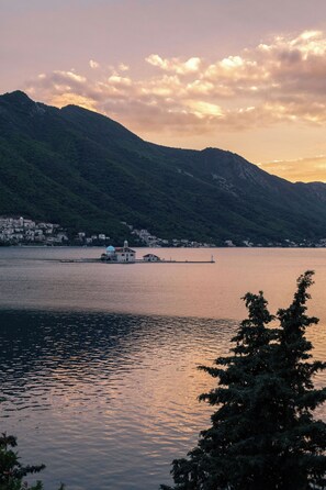 A calm lake with a small island and a distant mountain range.