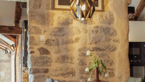 A rustic dining area with a stone wall, wooden table, and chairs. A pendant light hangs above the table, and a vase with flowers is on the table. - Step to Kotor Bay Perast (Perast)