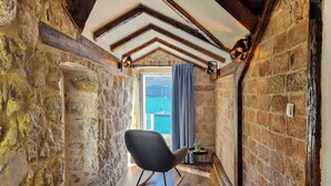 Un cuarto acogedor con paredes de piedra vista, techo de madera y vista al mar a través de un ventanal amplio.
