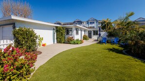 A residential property with a well-maintained lawn, a covered patio area, and a front yard with various plants and a small tree. - Carlsbad Beach Bungalows - 4BRs, Outdoor Living, Walk to Beach, Pet-Friendly (Carlsbad)