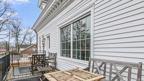 A wooden deck with a table and chairs, a large window, and a railing. - The Pasfield House - Historic Mansion: The Bitsy (Springfield)