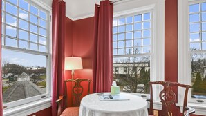 A room with a round table, a lamp, and a chair, with a view of a building and trees outside. - The Pasfield House - Historic Mansion: The Bitsy (Springfield)