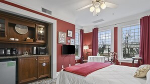 A hotel room with a bed, a desk, a TV, and a kitchenette. - The Pasfield House - Historic Mansion: The Bitsy (Springfield)