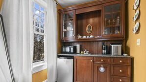 A kitchen with wooden cabinets, a microwave, a dishwasher, and a coffee maker. - Pasfield House Historic Mansion: The George Suite (Springfield)