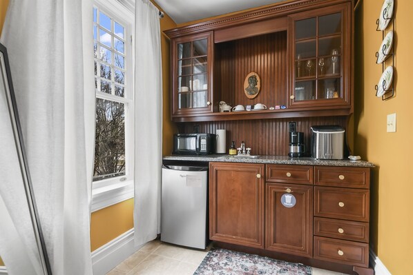A kitchen with wooden cabinets, a microwave, a dishwasher, and a coffee maker. - Pasfield House Historic Mansion: The George Suite (Springfield)