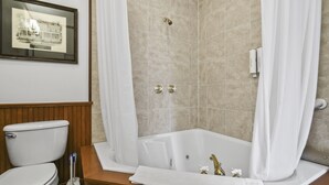 A bathroom with a bathtub, toilet, and a framed picture on the wall. - Pasfield House Historic Mansion: The George Suite (Springfield)