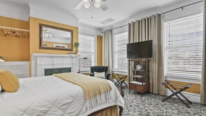A hotel room with a large bed, a television, a fireplace, and a window with blinds. - Pasfield House Historic Mansion: The George Suite (Springfield)