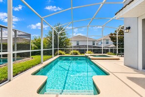 A swimming pool with a clear blue water, surrounded by a white fence and a covered area with a roof. - 5 Bed In Champions Gate, Modern Decor, Kid Themed Rooms, Game Room, Gated Resort! 5 Bedroom Home by RedAwning (Davenport)