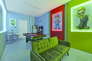Quarto com mesa de bilhar, sofá verde e decoração temática do Mario.