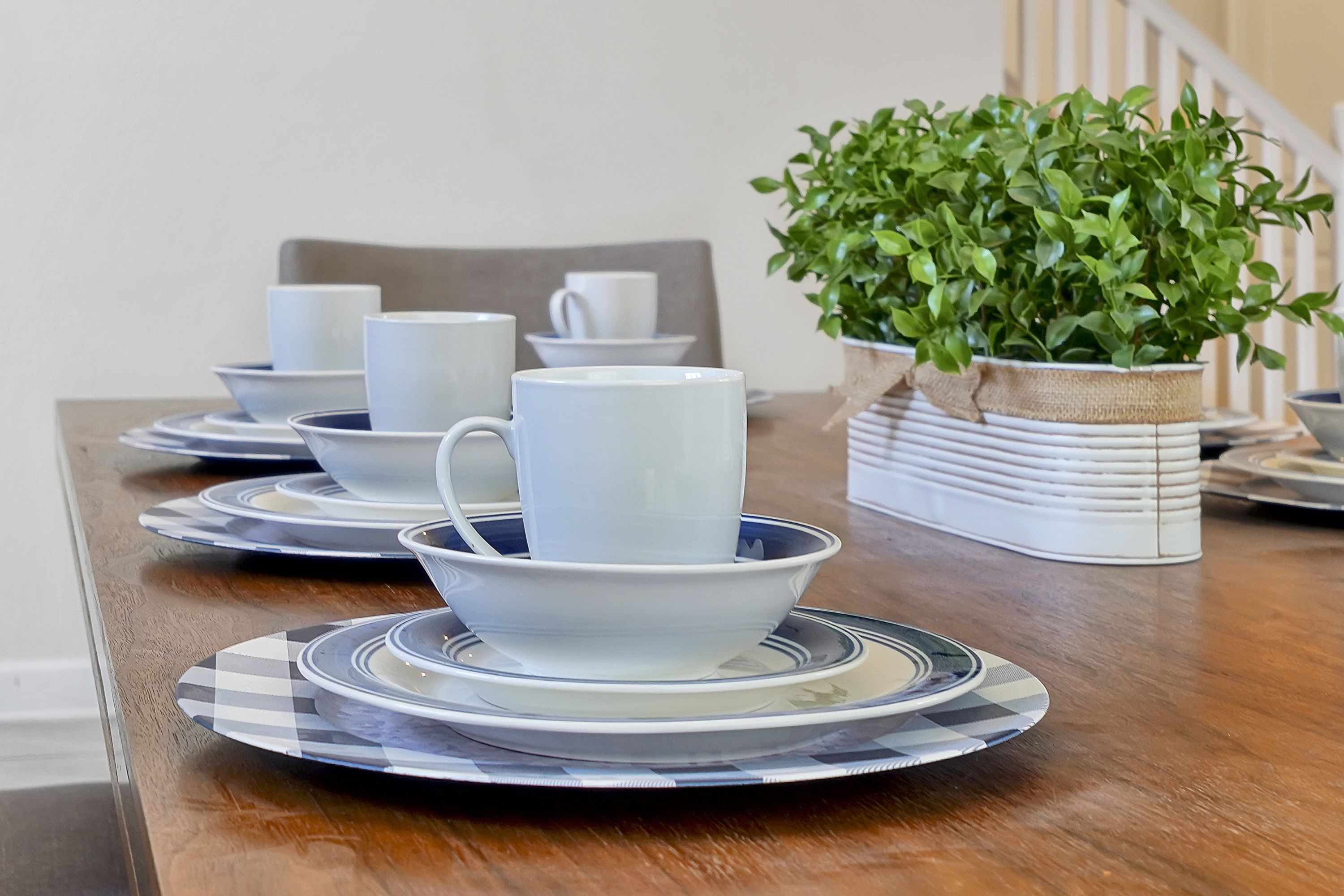 A dining table with white plates, bowls, and cups arranged for a meal.