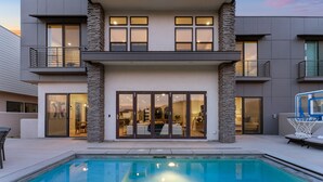 Una casa moderna de dos pisos con una piscina al frente.