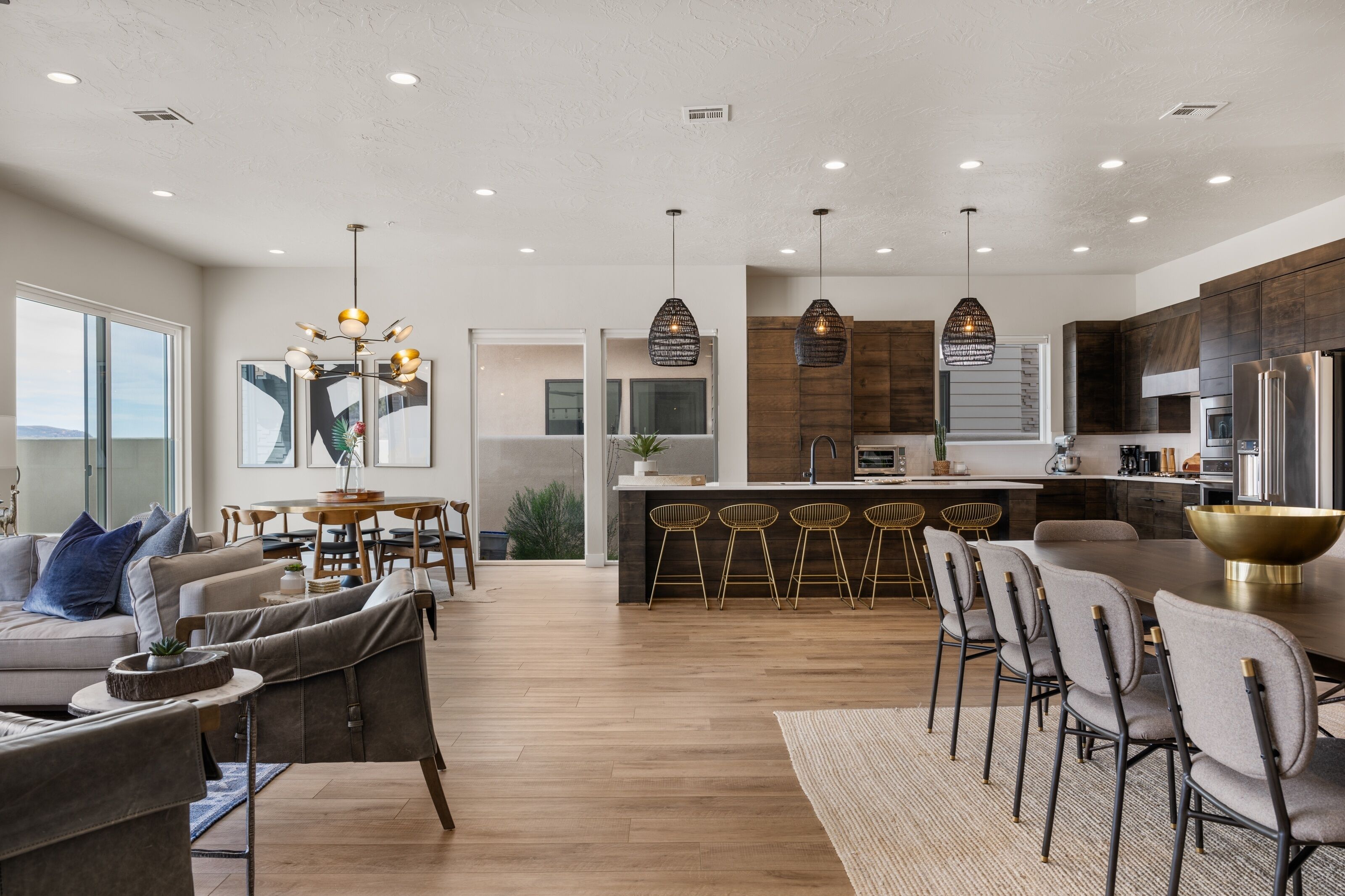 A modern kitchen with a central island, bar stools, and pendant lighting.