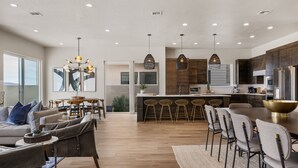 Una cocina moderna con una isla central, taburetes de bar e iluminación colgante.