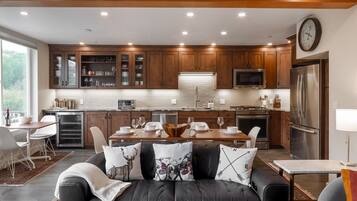 A modern kitchen with wooden cabinets, a stainless steel refrigerator, and a dining area with a table set for four.