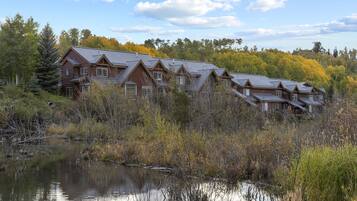 A large lodge with multiple buildings, surrounded by a natural landscape and a body of water.