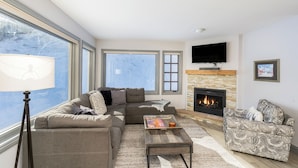 A living room with a fireplace, a sofa, a coffee table, and a TV. - Etta Place 111 2 Bedroom Condo by RedAwning (Telluride)