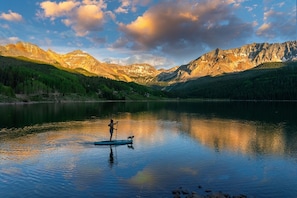 A serene lake with mountains in the background and a person paddleboarding.