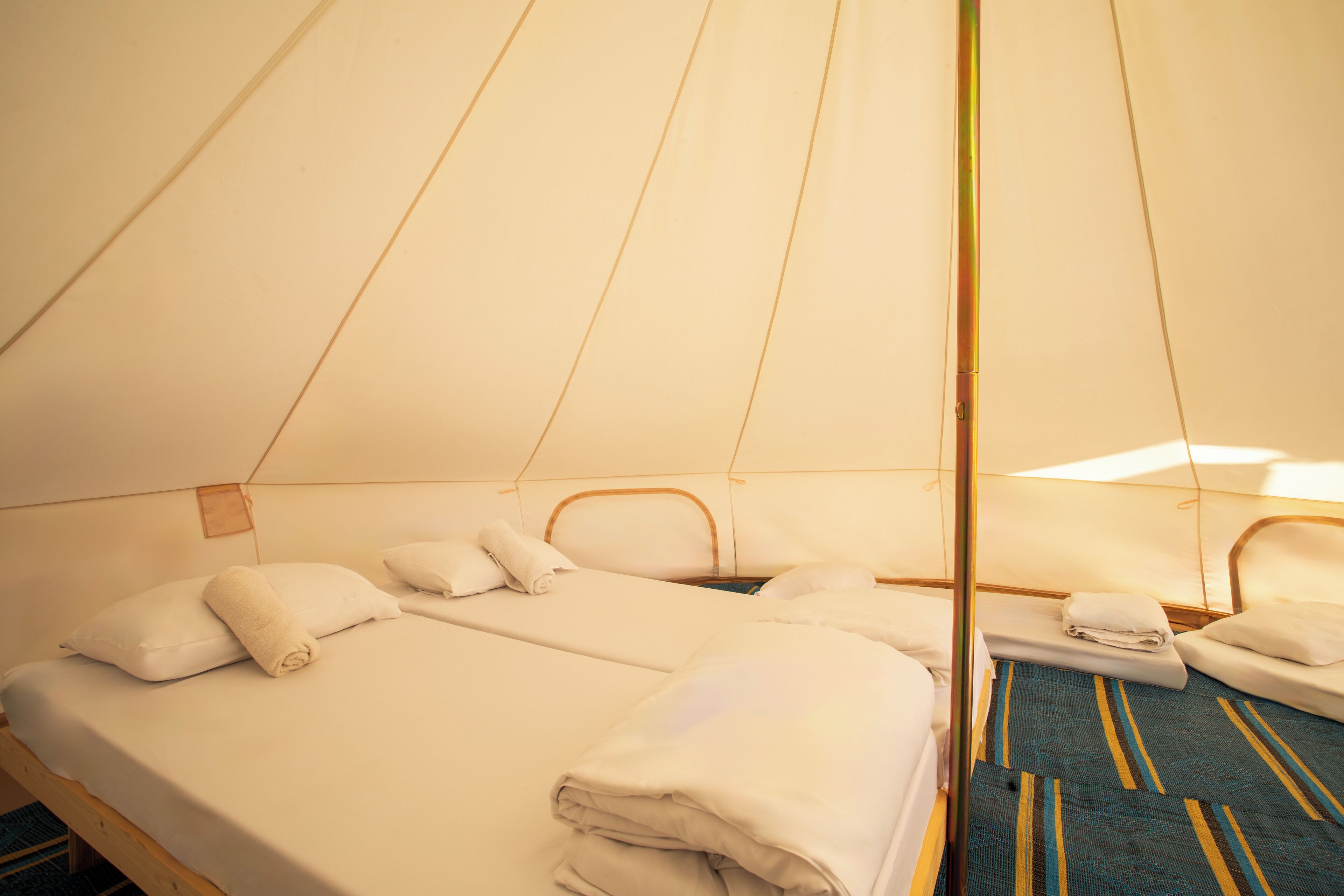 A tent-style room with two beds, each with pillows and blankets.