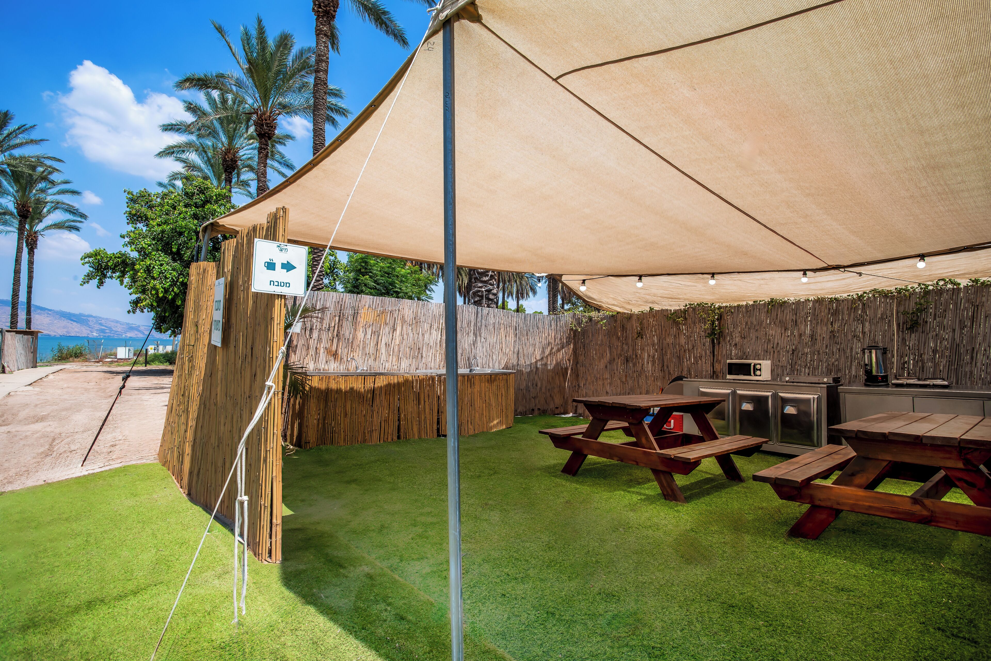 An outdoor patio with picnic tables, a barbecue grill, and a view of the mountains.