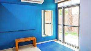 Een kamer met blauwe wanden, een houten bank, een groot raam en een airconditioning.