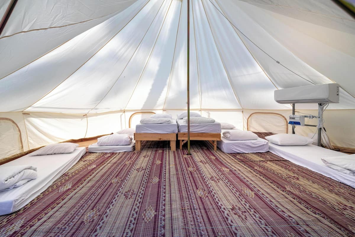 A tent with two beds, a heater, and a window.