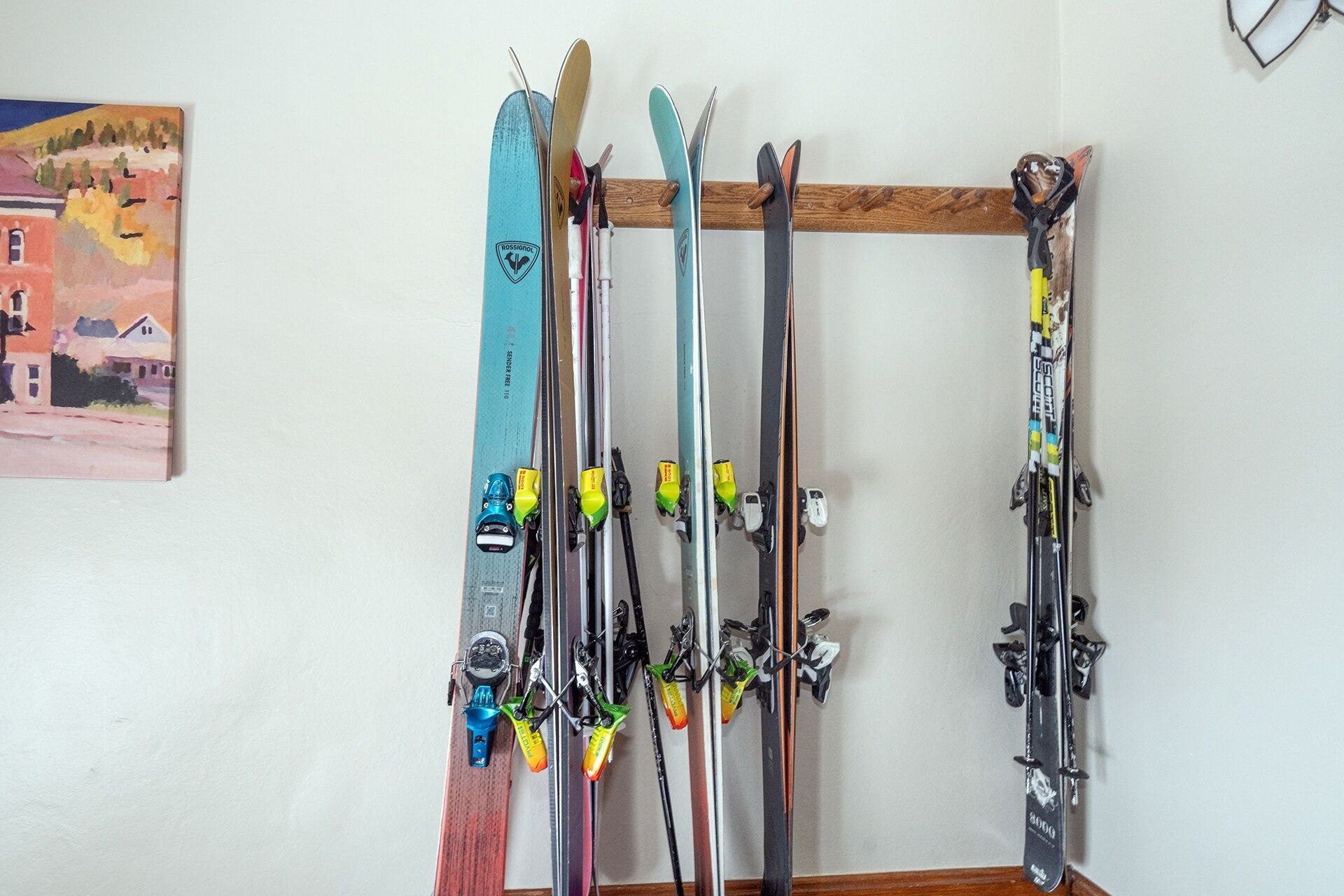 A wall-mounted ski rack with multiple pairs of skis and ski poles.