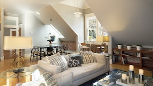 Un amplio loft con techos altos, zona de comedor, un conjunto de sofás y una estantería.