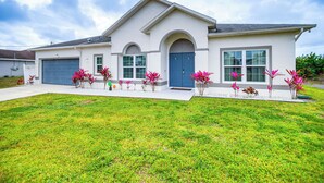 A modern two-story house with a garage, large windows, and a well-maintained lawn. - Lanai, Private Pool: Lehigh Acres Home (Lehigh Acres)