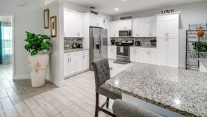 A modern kitchen with white cabinets, stainless steel appliances, and a granite countertop. - Lanai, Private Pool: Lehigh Acres Home (Lehigh Acres)