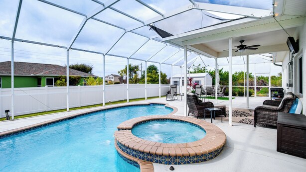A covered swimming pool with a hot tub, outdoor furniture, and a patio area. - Lanai, Private Pool: Lehigh Acres Home (Lehigh Acres)