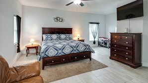 A bedroom with a bed, a ceiling fan, a dresser, a TV, and a window with curtains. - Lanai, Private Pool: Lehigh Acres Home (Lehigh Acres)