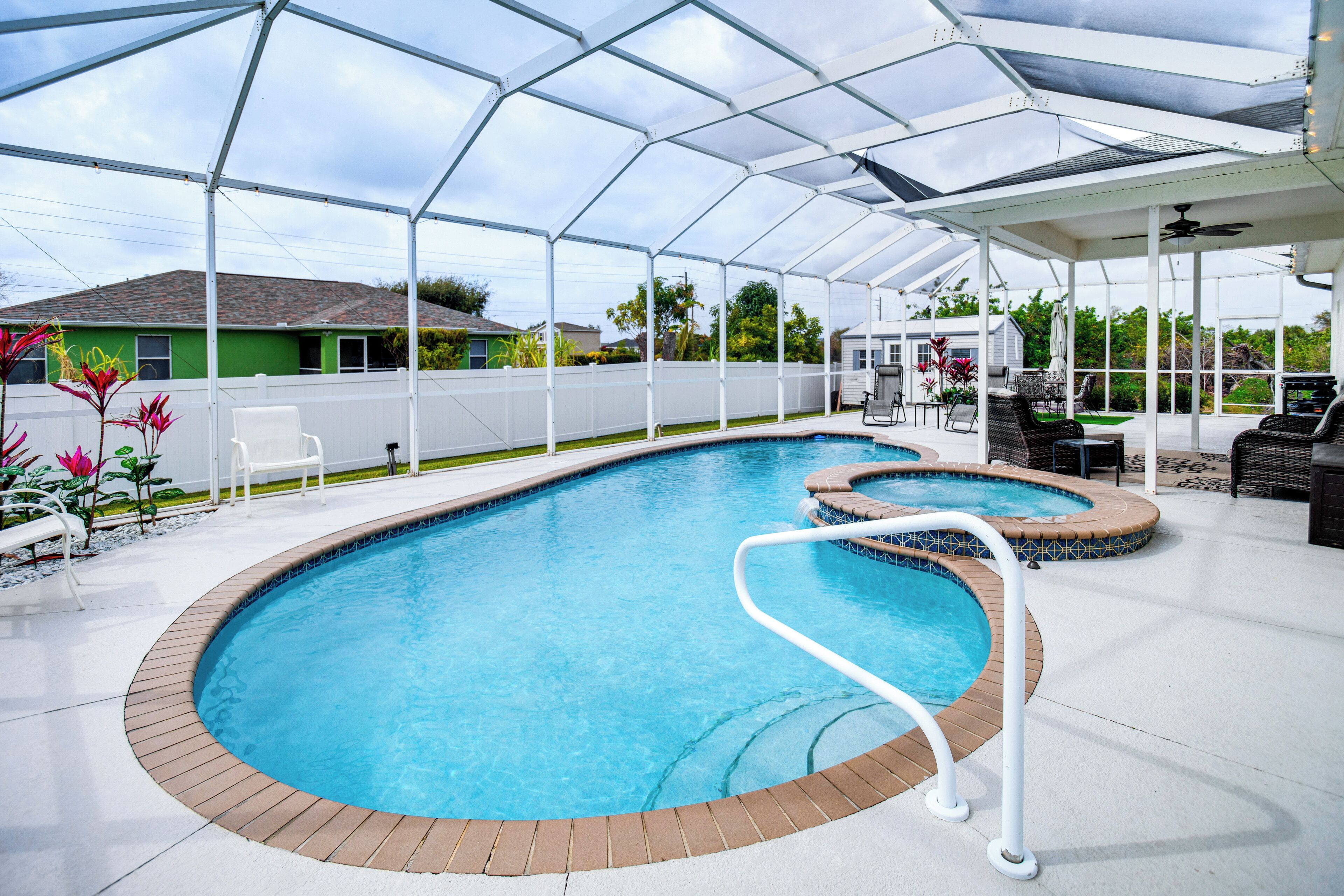 Piscina exterior techada con terraza blanca, sillas de descanso y un jacuzzi.