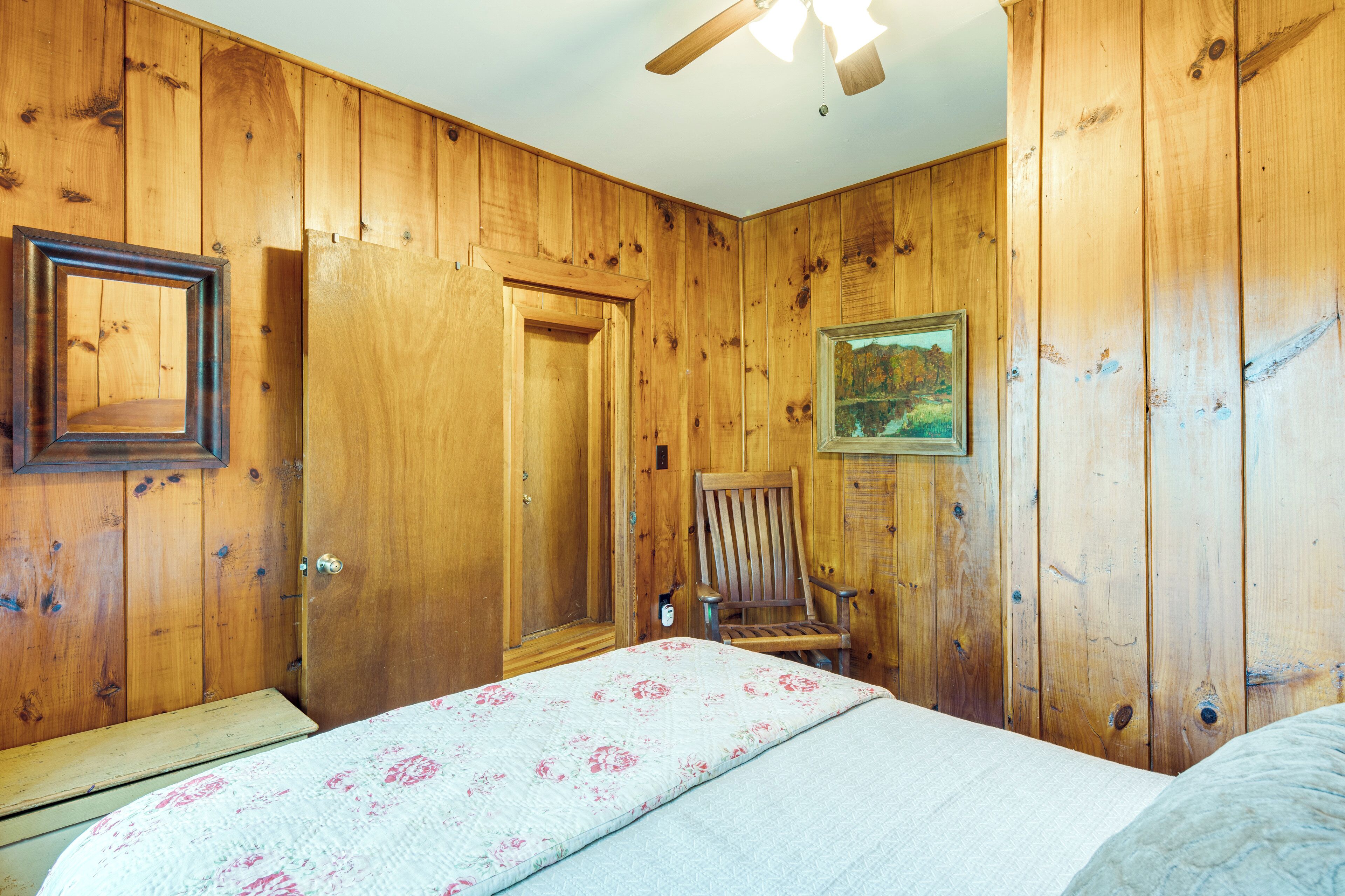 Una habitación con paneles de madera, una cama, una silla y una puerta.