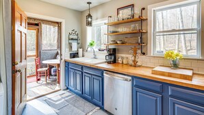 A kitchen with blue cabinets, a wooden countertop, and a window with a view of trees. - Peaceful Hendersonville Cabin - Hot Tub & Fire Pit (Hendersonville)