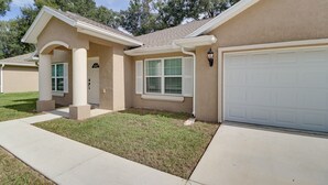 A residential house with a garage, a front porch, and a well-maintained lawn. - Ocala Retreat: 4 Mi to World Equestrian Center! (Ocala)