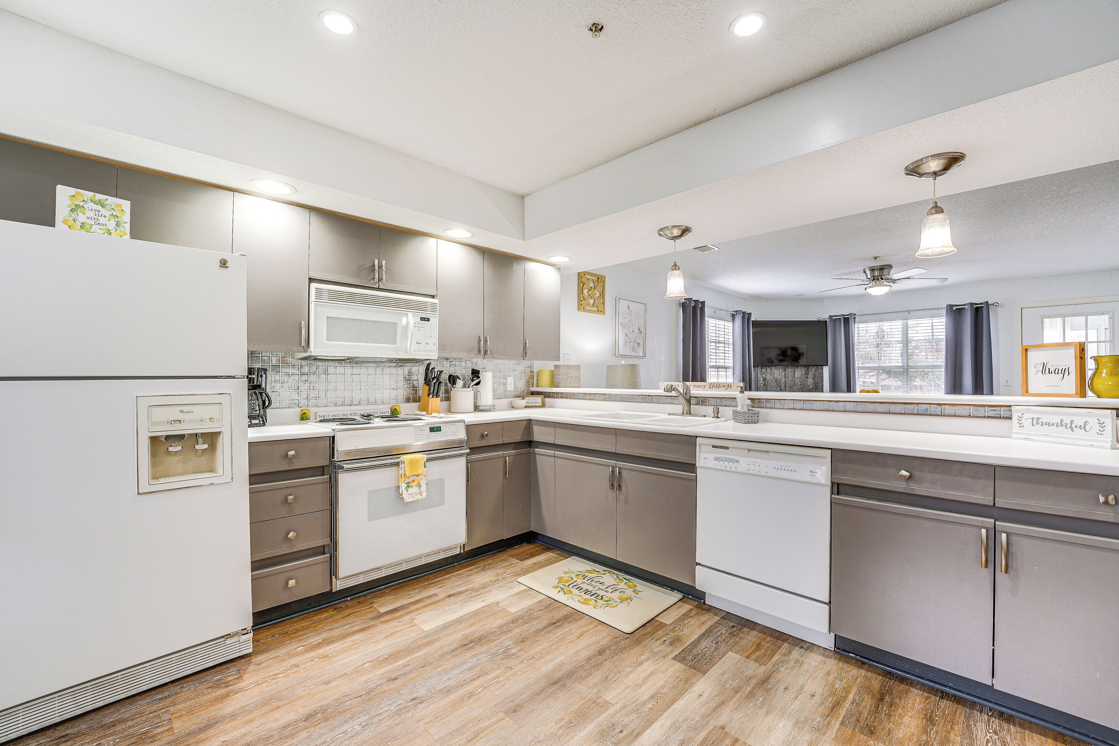 Una cocina moderna con electrodomésticos blancos, armarios grises y piso de madera.