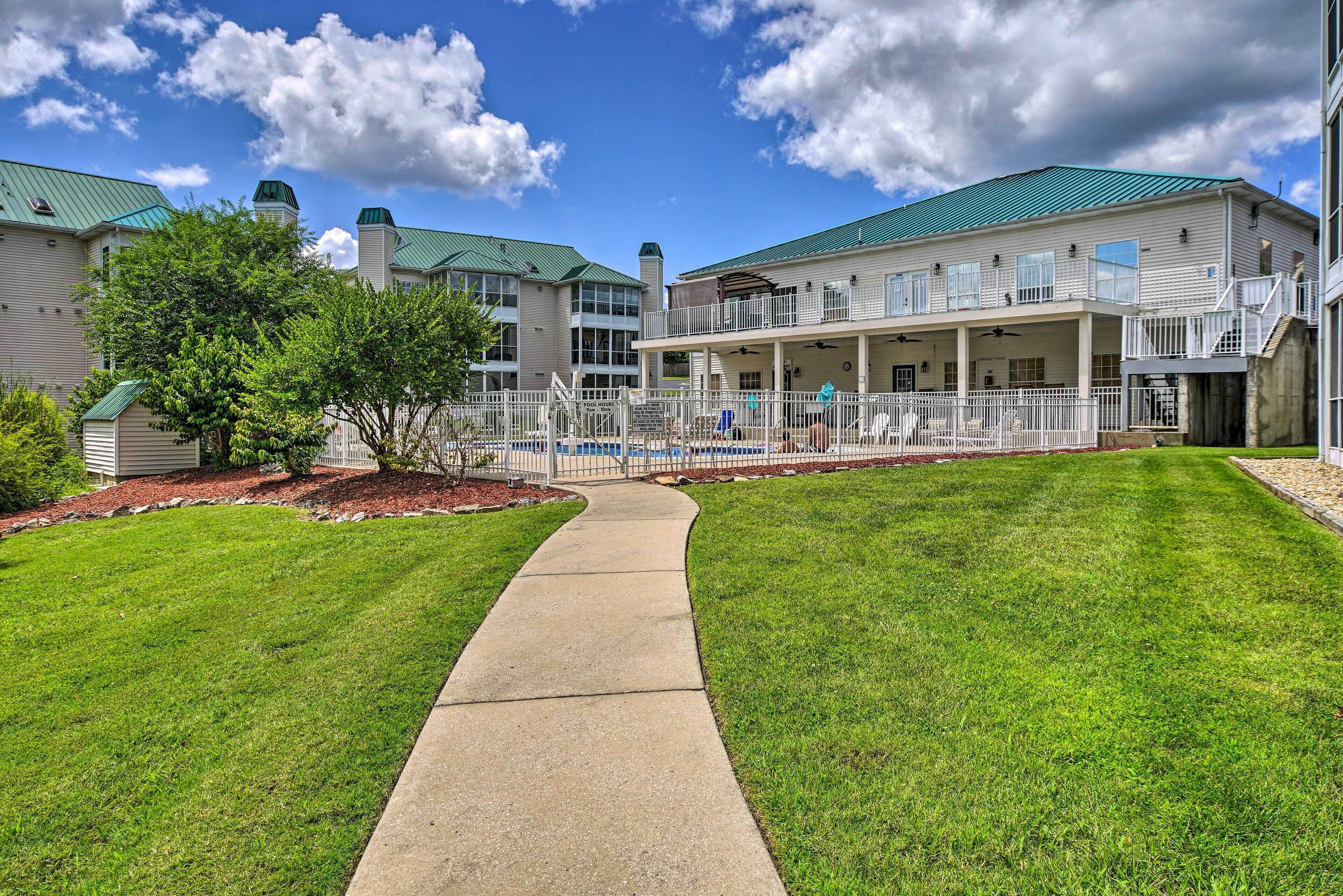 A hotel with a covered outdoor area, a concrete pathway, and a well-maintained lawn.