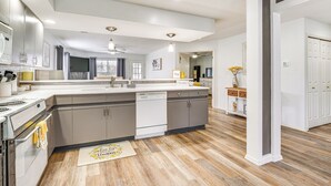 Uma cozinha moderna com ilha central, eletrodomésticos embutidos e piso de madeira.